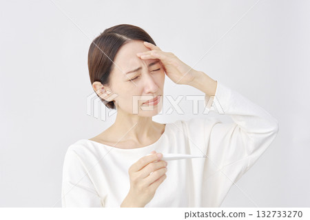 Woman measuring temperature with a thermometer on a white background Woman measuring temperature with a thermometer on a white background 132733270