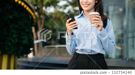 Asian woman with a smile standing holding notepad and tablet at out side office. big city on business center 132734140