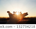 Bright sunlight shining through hands and sunrise background for New Year 2026 132734218