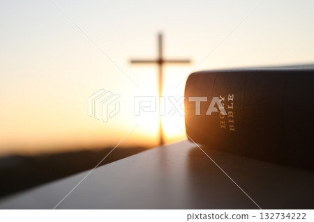 A bright New Year's sunrise with the Holy Cross of Jesus Christ and a Bible in the background 132734222