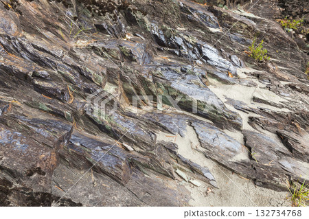 Layered slate rocks meet light sand in a rugged coastal scene. Altai, Russia Layered slate rocks meet light sand in a rugged coastal scene. Altai, Russia 132734768