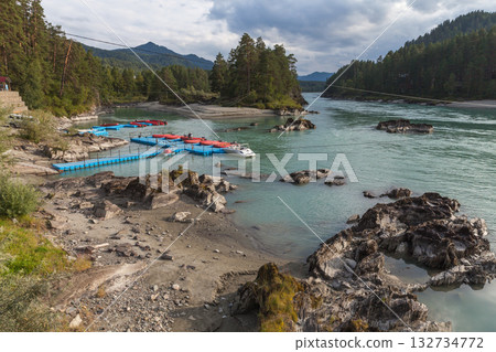 A tranquil riverside scene with a rocky shore, clear turquoise water, Altai Republic A tranquil riverside scene with a rocky shore, clear turquoise water, Altai Republic 132734772