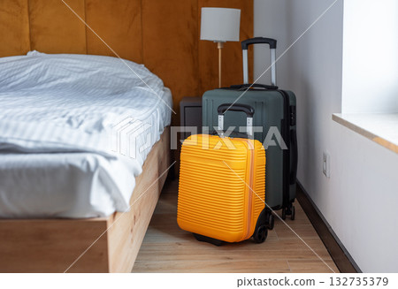 Luggage standing beside bed in modern hotel room 132735379