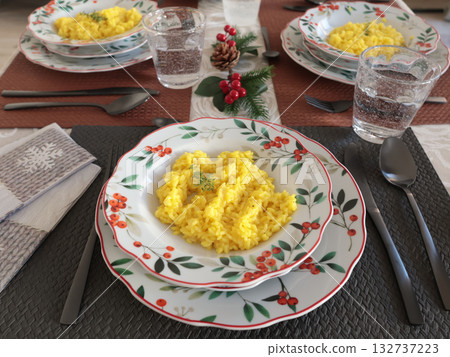 Table setting with bright tableware, berries, and twigs. Saffron risotto on plate. Traditional Italian food. Aesthetics and lifestyle. Interior design. Table setting with bright tableware, berries, and twigs. Saffron risotto on plate. Traditional Italian food. Aesthetics and lifestyle. Interior design. 132737223