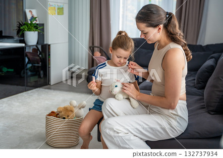 Mother fixing her daughter favorite toy while the girl helps. Warm family moment full of love, care, and childhood memories and emotional value Mother fixing her daughter favorite toy while the girl helps. Warm family moment full of love, care, and childhood memories and emotional value 132737934