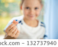 Girl showing finger heart gesture in a portrait with hand in sharp focus and face blurred in the background. Youth expressing love and modern pop culture trend from Gen Z to younger kids. 132737940