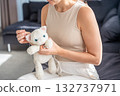 Young woman sewing an old plush toy at home with needle and thread. Sustainable lifestyle and conscious consumption as part of eco friendly and mindful living. 132737971