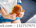A plush capybara toy held in a child hands. The image reflects Gen Z love for internet-inspired mascots and the aesthetic comfort culture of soft toys. 132737973