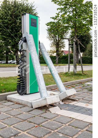 Broken and bent metal safety posts in front of an electric vehicle charging station, symbolizing 132738524