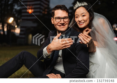 Interracial wedding couple showing engagement rings after ceremony 132739148