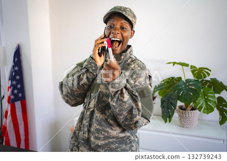 Excited military woman sharing pregnancy test result on the phone Excited military woman sharing pregnancy test result on the phone 132739243