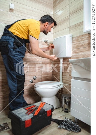 Plumber repairing toilet cistern in a bathroom 132739277