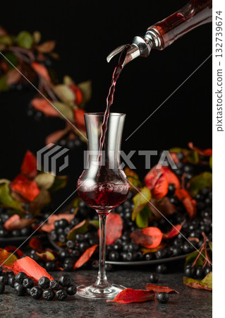 Black chokeberry liqueur and fresh berries on a black table. Black chokeberry liqueur and fresh berries on a black table. 132739674