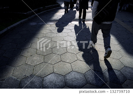 Shadows of people stretching across the hexagonal tiled sidewalk - City snapshots 132739710