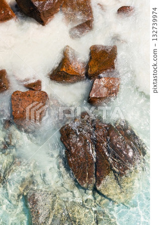 Beautiful sunlight shining on rocks in clear blue water at a tranquil beach location during the afternoon hours in a serene natural setting Beautiful sunlight shining on rocks in clear blue water at a tranquil beach location during the afternoon hours in a serene natural setting 132739974
