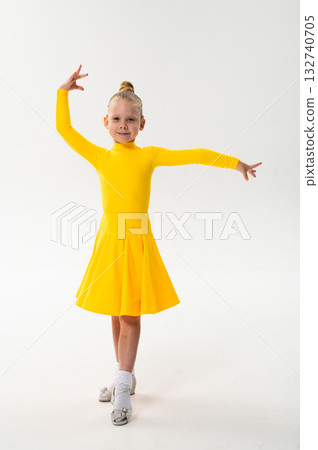 Smiling child in bright yellow practicing choreography with hearing device. Confidence, concentration, and harmony of movement despite deafness, showing inclusion and technological progress in 132740705