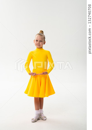Smiling child in bright yellow practicing choreography with hearing device. Confidence, concentration, and harmony of movement despite deafness, showing inclusion and technological progress in Smiling child in bright yellow practicing choreography with hearing device. Confidence, concentration, and harmony of movement despite deafness, showing inclusion and technological progress in 132740708
