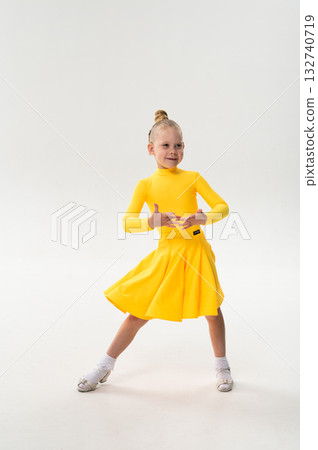 Smiling child in bright yellow practicing choreography with hearing device. Confidence, concentration, and harmony of movement despite deafness, showing inclusion and technological progress in 132740719