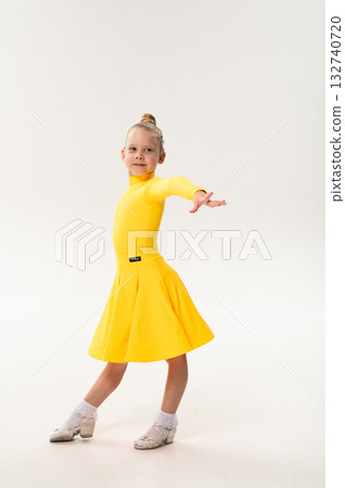 Little girl in yellow dress dancing with cochlear implant. Overcoming hearing loss through rhythm, art, inclusion, and strength of spirit in artistic gymnastics and ballroom dance. 132740720