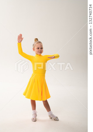 Little girl in yellow dress dancing with cochlear implant. Overcoming hearing loss through rhythm, art, inclusion, and strength of spirit in artistic gymnastics and ballroom dance. 132740734