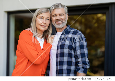 Two people standing at the house entrance and looking contented 132740760