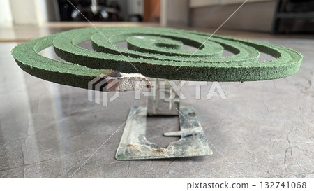 Stylishly designed Green Spiral Mosquito Coil resting on a convenient Stand for use Stylishly designed Green Spiral Mosquito Coil resting on a convenient Stand for use 132741068
