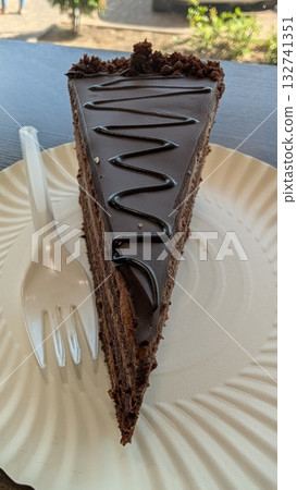 Indulge in a Delicious Slice of Chocolate Cake Topped with an Elegant Drizzle of Frosting Indulge in a Delicious Slice of Chocolate Cake Topped with an Elegant Drizzle of Frosting 132741351