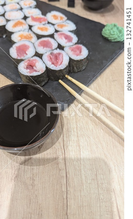 A Delicious Sushi Spread Beautifully Arranged on a Slate with Soy Sauce and Chopsticks for Enjoyment 132741451