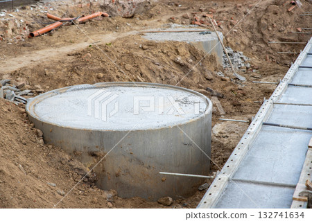 Concrete foundation poured into metal formwork at construction site. Steel rods, braces and rebar elements create strong structure supported by soil and wooden beams Concrete foundation poured into metal formwork at construction site. Steel rods, braces and rebar elements create strong structure supported by soil and wooden beams 132741634