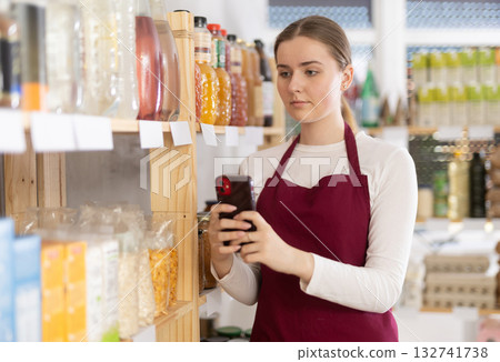 Girl merchandiser photographs shelves with goods and creates photo report of rearrange work result Girl merchandiser photographs shelves with goods and creates photo report of rearrange work result 132741738