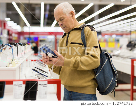 elderly grayhaired man pensioner examining counter with electronic gadgets and tablets in showroom of digital goods store 132741752