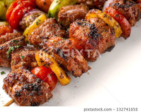 Close-up of delicious grilled meat skewers (kebab) with bell peppers, tomatoes, and onions. Appetizing barbecue food isolated on a white background. 132741858