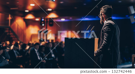 Speaker giving a talk on corporate business conference. Unrecognizable people in audience at conference hall. Business and Entrepreneurship event. Speaker giving a talk on corporate business conference. Unrecognizable people in audience at conference hall. Business and Entrepreneurship event. 132742446