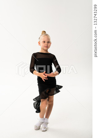 Little girl in black latin dance dress performing graceful pose with cochlear implant. Overcoming hearing loss through movement, inclusion, and confidence in art and rhythmic self-expression. Little girl in black latin dance dress performing graceful pose with cochlear implant. Overcoming hearing loss through movement, inclusion, and confidence in art and rhythmic self-expression. 132743299