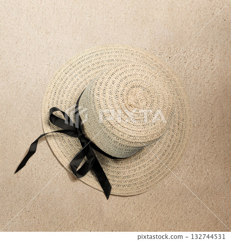 Straw hat with a black ribbon on a beach sand background. Concept of travel, summer, or vacation Straw hat with a black ribbon on a beach sand background. Concept of travel, summer, or vacation 132744531