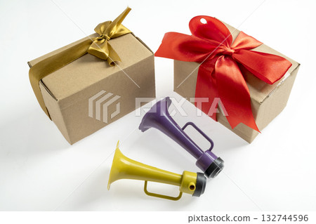 Plastic horn and gift box isolated over a white background. Concept of a party or a holiday celebration Plastic horn and gift box isolated over a white background. Concept of a party or a holiday celebration 132744596
