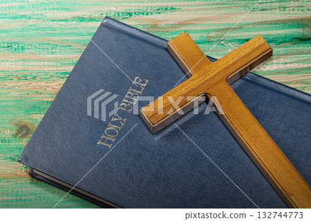Blue book of the Holy bible and a Christian cross on a wooden table. Symbol of faith in God. Concept of Spirituality, Christianity, religion, faith, Jesus, or belief 132744773