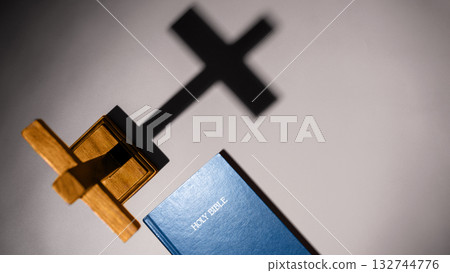 Blue book of the Holy bible and Christian cross. Standing on the table with a dark background. Symbol of faith in God. Concept of Spirituality, Christianity, religion, faith, Jesus, or belief Blue book of the Holy bible and Christian cross. Standing on the table with a dark background. Symbol of faith in God. Concept of Spirituality, Christianity, religion, faith, Jesus, or belief 132744776