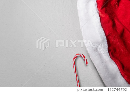 Santa hat with a candy cane on a white background. Mockup or Copy space for holiday greetings or winter themes Santa hat with a candy cane on a white background. Mockup or Copy space for holiday greetings or winter themes 132744792