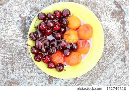 Sweet cherries and apricots on a plate. Sweet cherries and apricots on a plate. 132744818