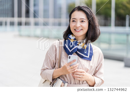 A businesswoman operating a smartphone in an office district 132744962