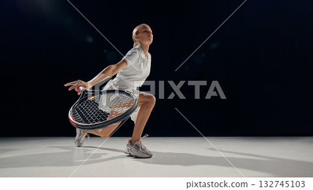 Female tennis player crouching defense low shot on dark background minimal light 132745103