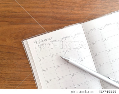 An open December schedule book and ballpoint pen on a desk An open December schedule book and ballpoint pen on a desk 132745355