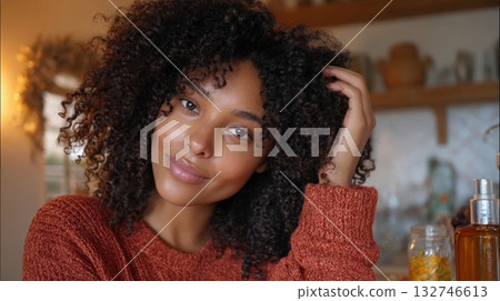 Woman with curly hair in a cozy autumn sweater posing naturally in a warm home setting 132746613
