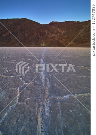 Salt Flats Cracked Surface and Distant Mountains under Blue Sky 132747059