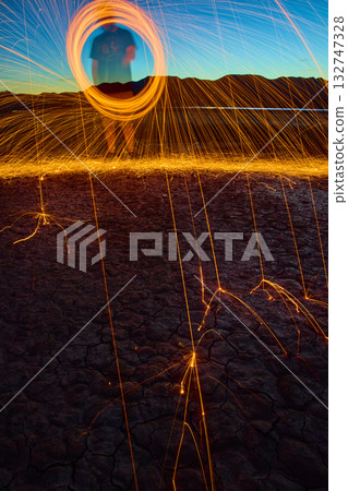 Steel Wool Sparks and Silhouette at Golden Hour on Cracked Desert Lake Bed Steel Wool Sparks and Silhouette at Golden Hour on Cracked Desert Lake Bed 132747328
