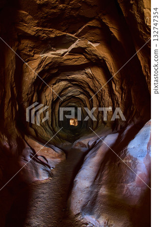 Hand Carved Desert Tunnel with Red Rock Walls and Distant Light Kanab Utah 132747354