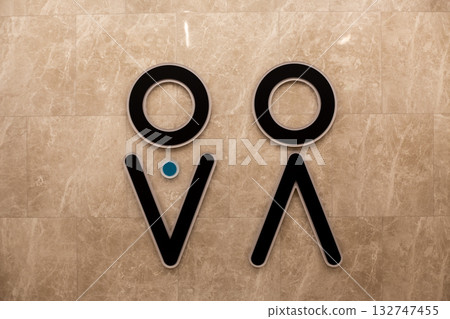 Wall with universal gender symbols for men and women indicating left for men and right for women in sex public restroom. Concept for hygiene and universal design for public accessible environment Wall with universal gender symbols for men and women indicating left for men and right for women in sex public restroom. Concept for hygiene and universal design for public accessible environment 132747455