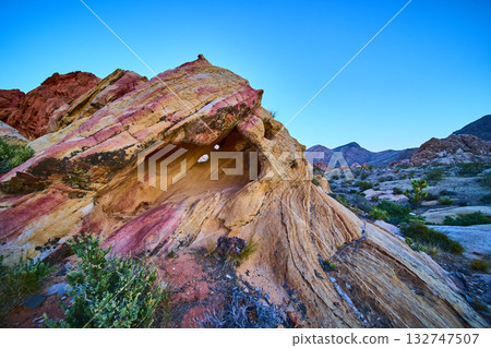 Desert Arch Formation with Colorful Sandstone and Distant Mountains 132747507