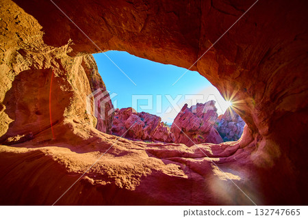 Sunburst Through Red Rock Arch at Golden Hour in Scenic Desert Landscape 132747665
